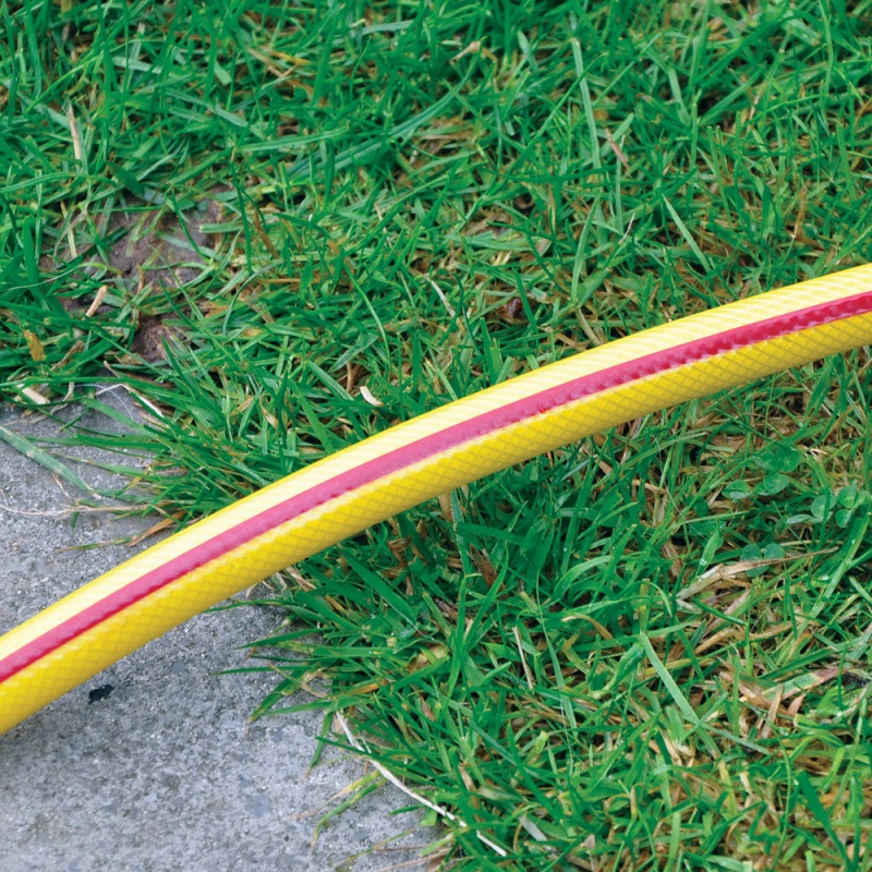 Yellow garden hose with red line on grass