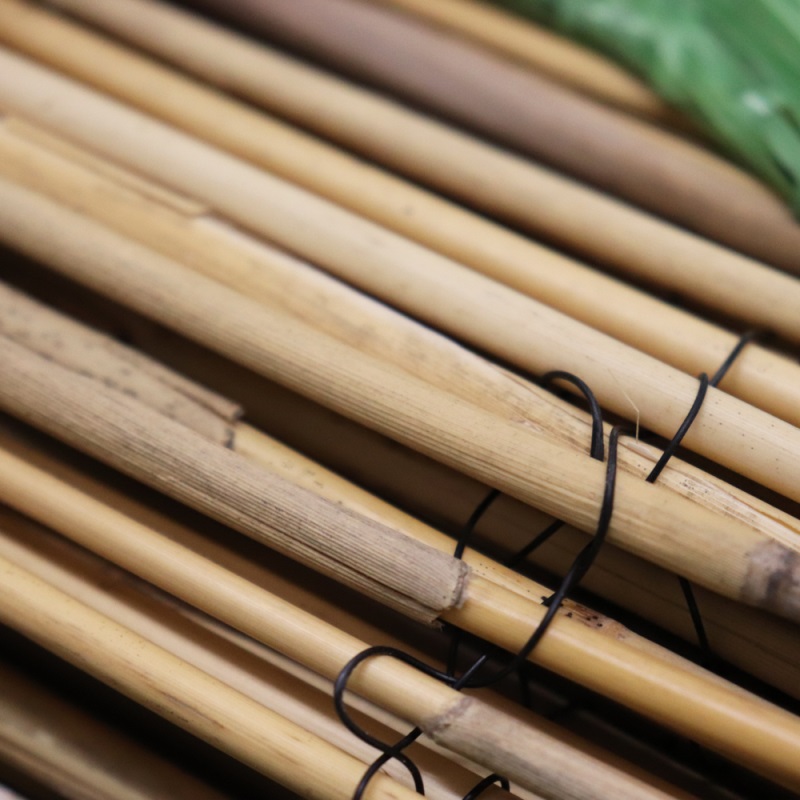 Close-up of natural reed garden fencing tied with black wire.