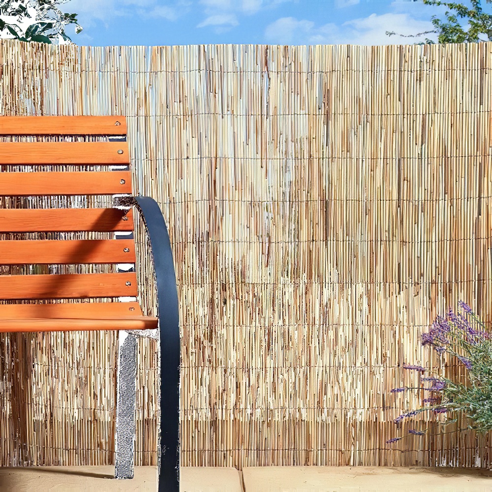 Reed garden fencing with a wooden bench and plants.