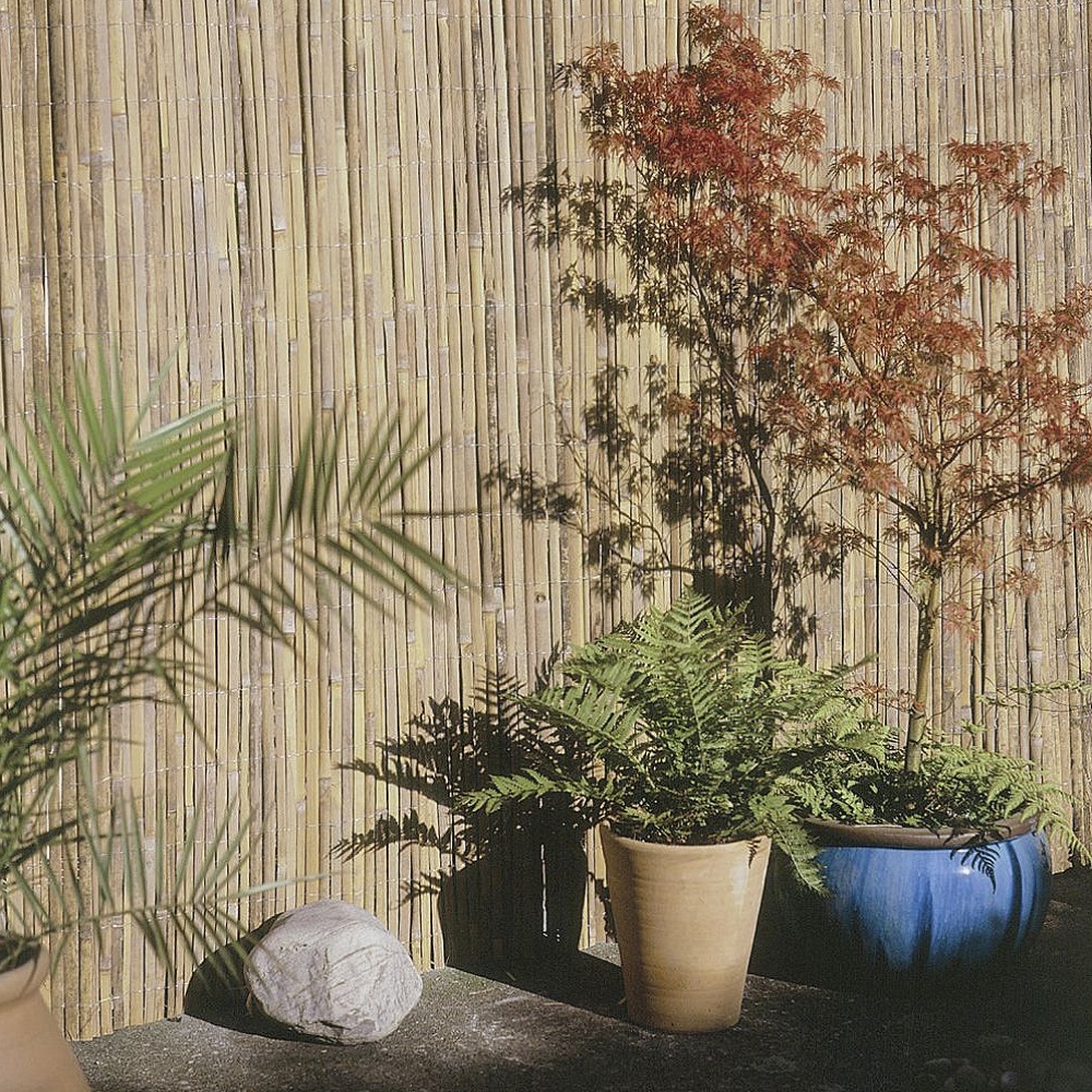 Natural reed garden fencing with potted plants in the foreground.