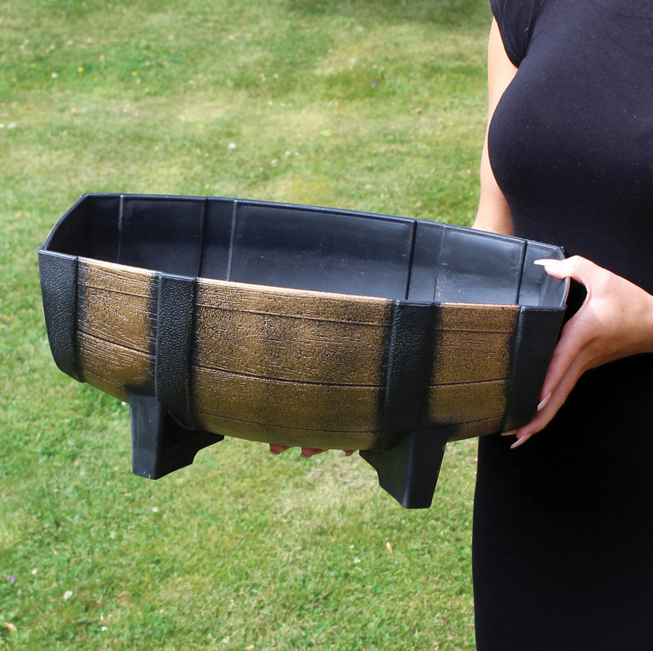Person holding a Kingfisher Garden Wood Effect Half Barrel Plastic Planter Trough on a grassy background.