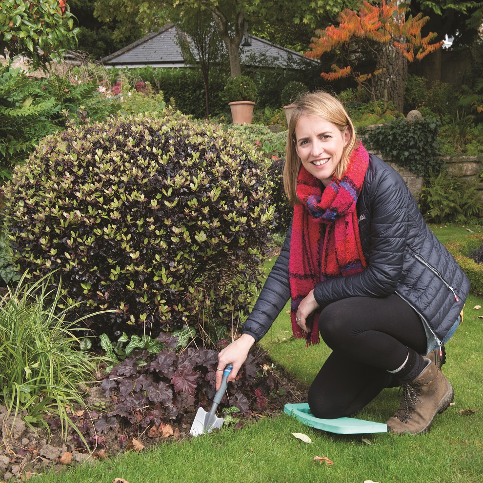 Person kneeling on a garden knee pad while gardening.
