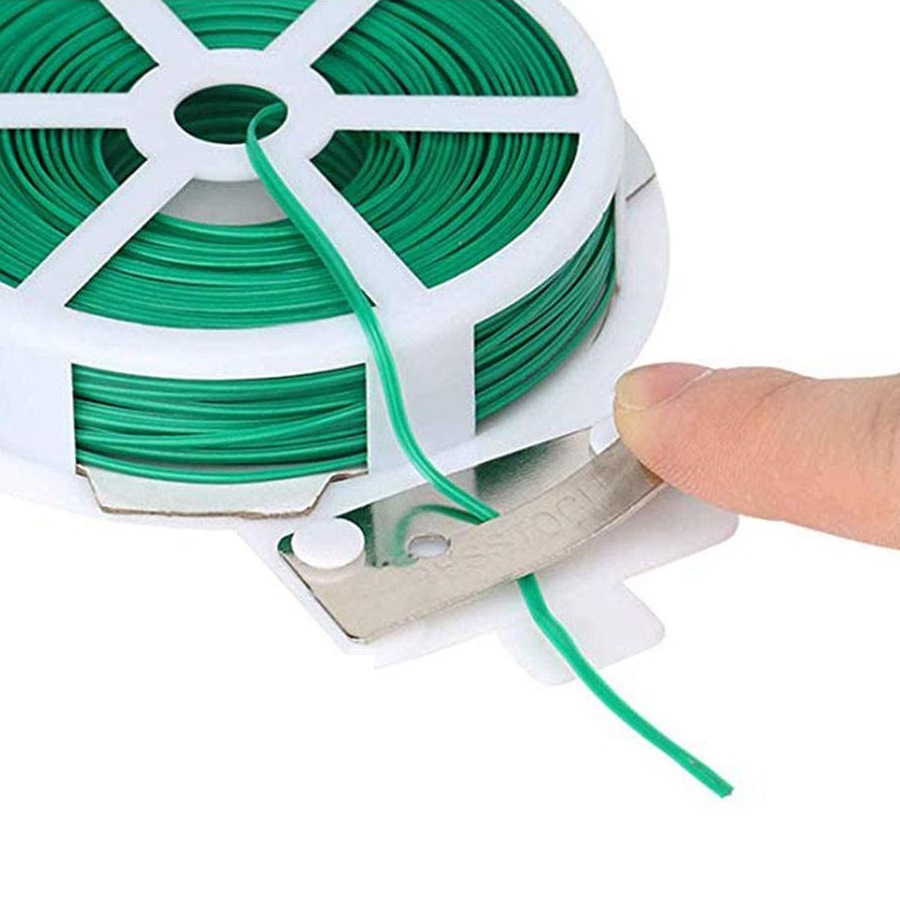 Close-up of a spool of green tie wire with a cutting tool for garden plant support.
