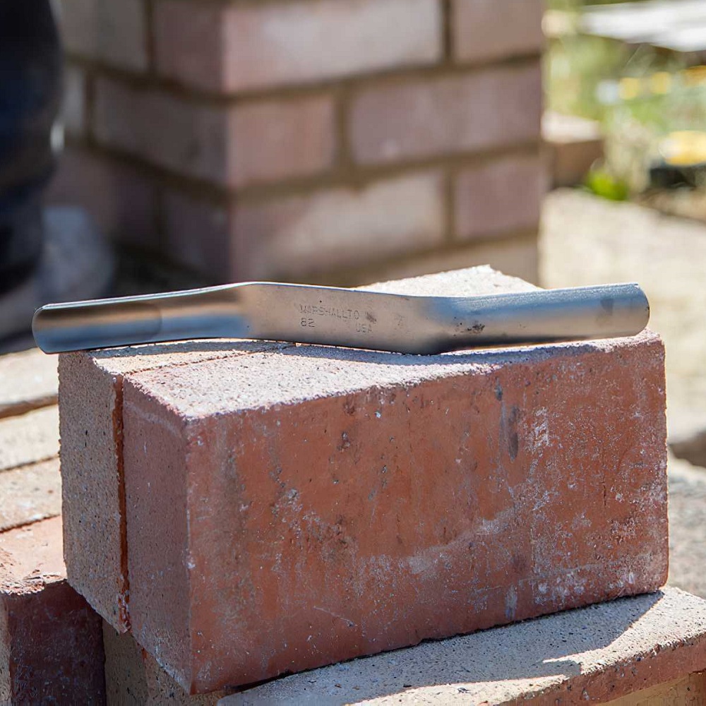 Marshalltown brick mortar jointer pointing iron resting on a red brick.