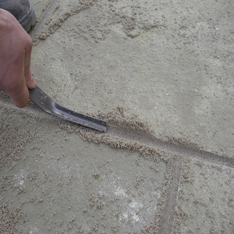 Person using a Marshalltown brick mortar jointer pointing iron on a concrete surface.