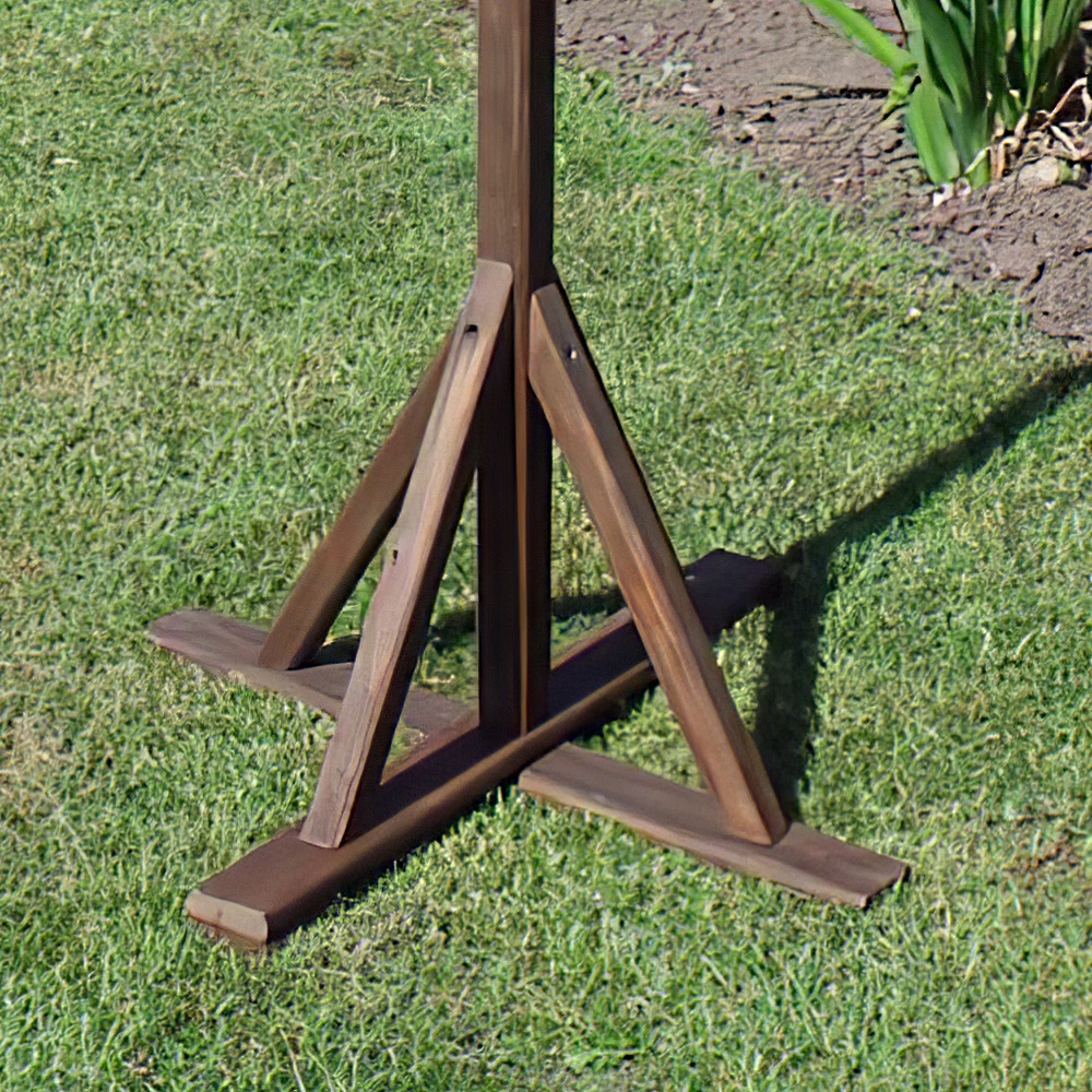 Wooden base of a rustic garden bird table on grass