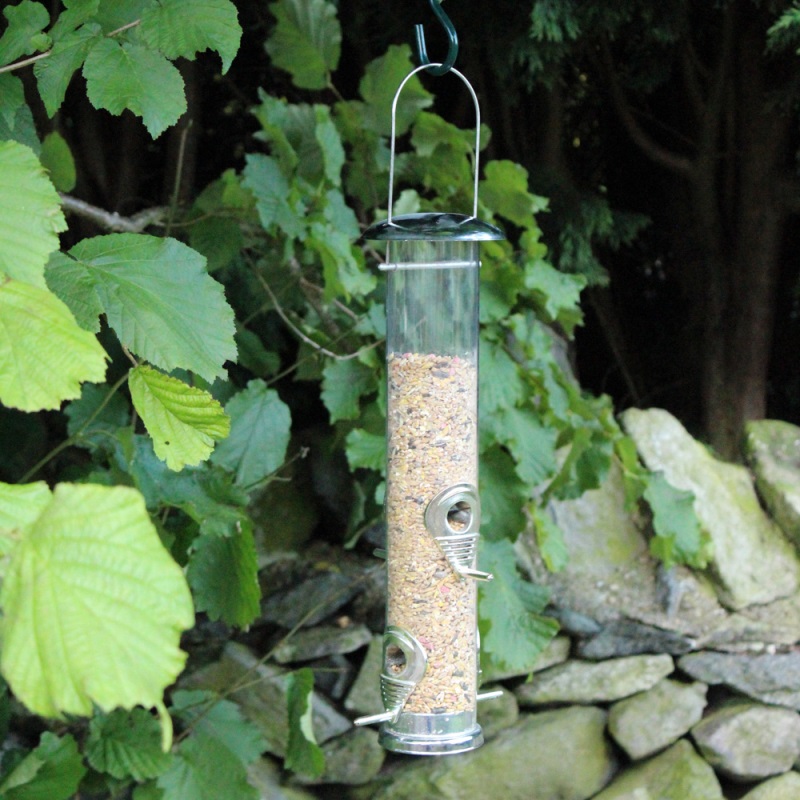 Bird feeder filled with Natures Market Wild Bird Food Seed Mix hanging in a garden.