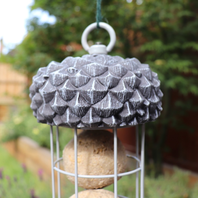 Close-up of a wild bird acorn suet fat ball feeder with a decorative acorn top and metal cage design.