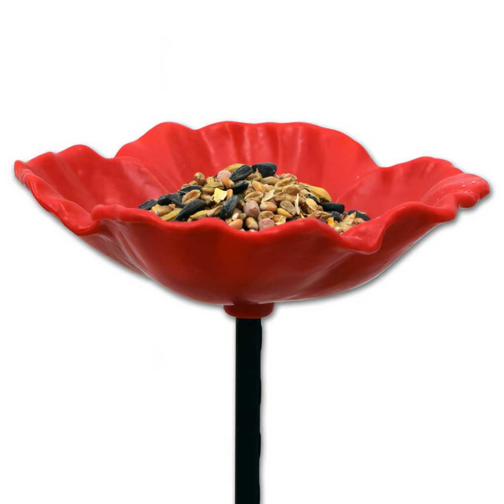 Red poppy-shaped bird feeder filled with mixed seeds on a stand.
