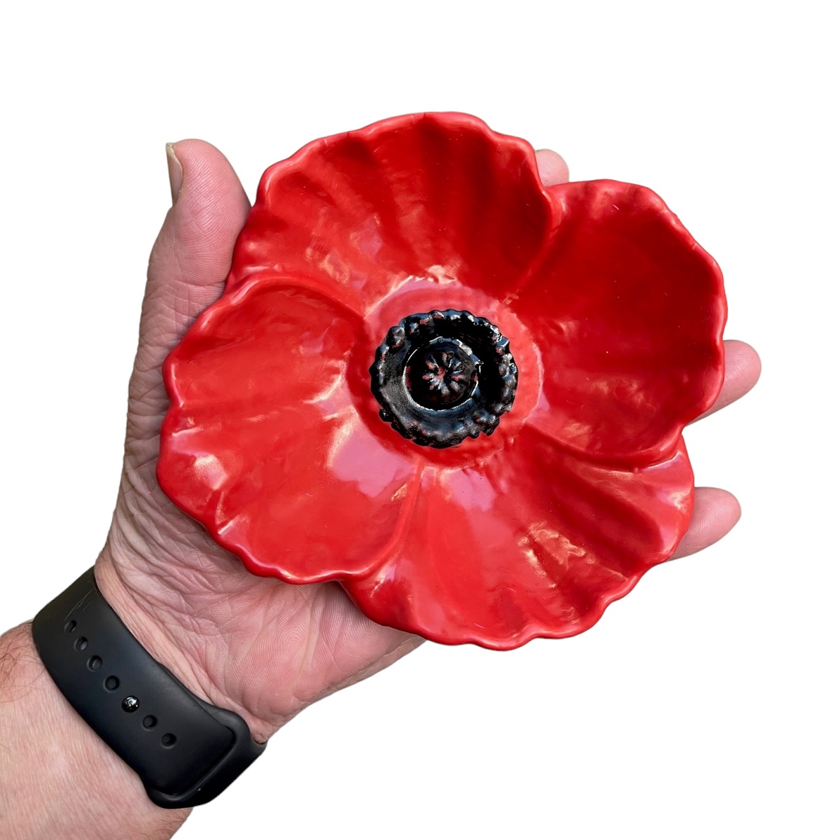 Hand holding a red poppy-shaped bird feeder.