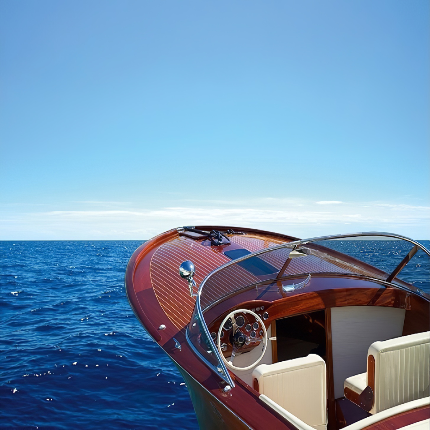 A wooden yacht with a high gloss finish sailing on the open sea under a clear blue sky.