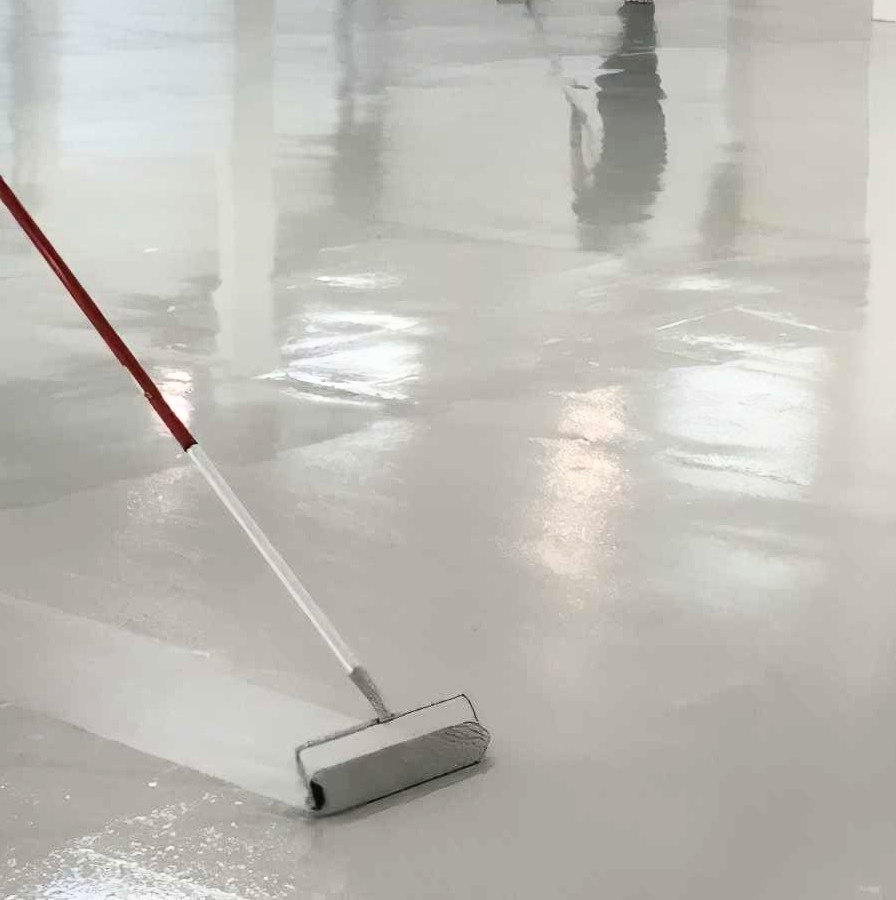 A 12 inch solvent resistant industrial paint roller sleeve applying paint on a smooth surface.