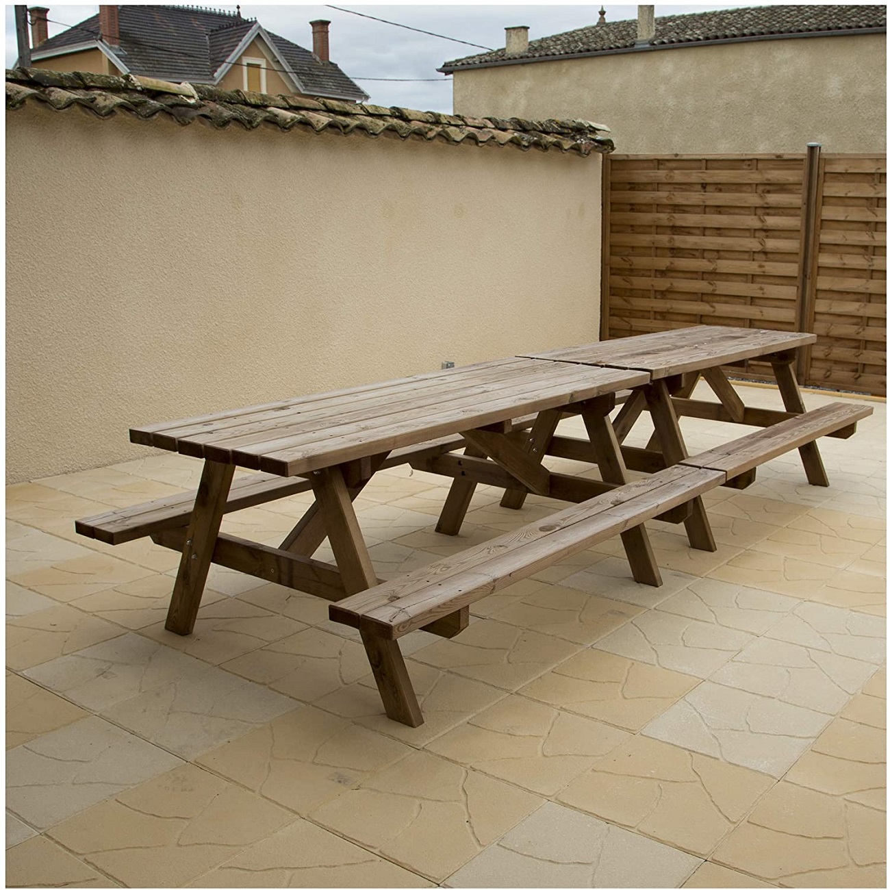 Outdoor wooden picnic table on a patio with Indian sandstone paving.