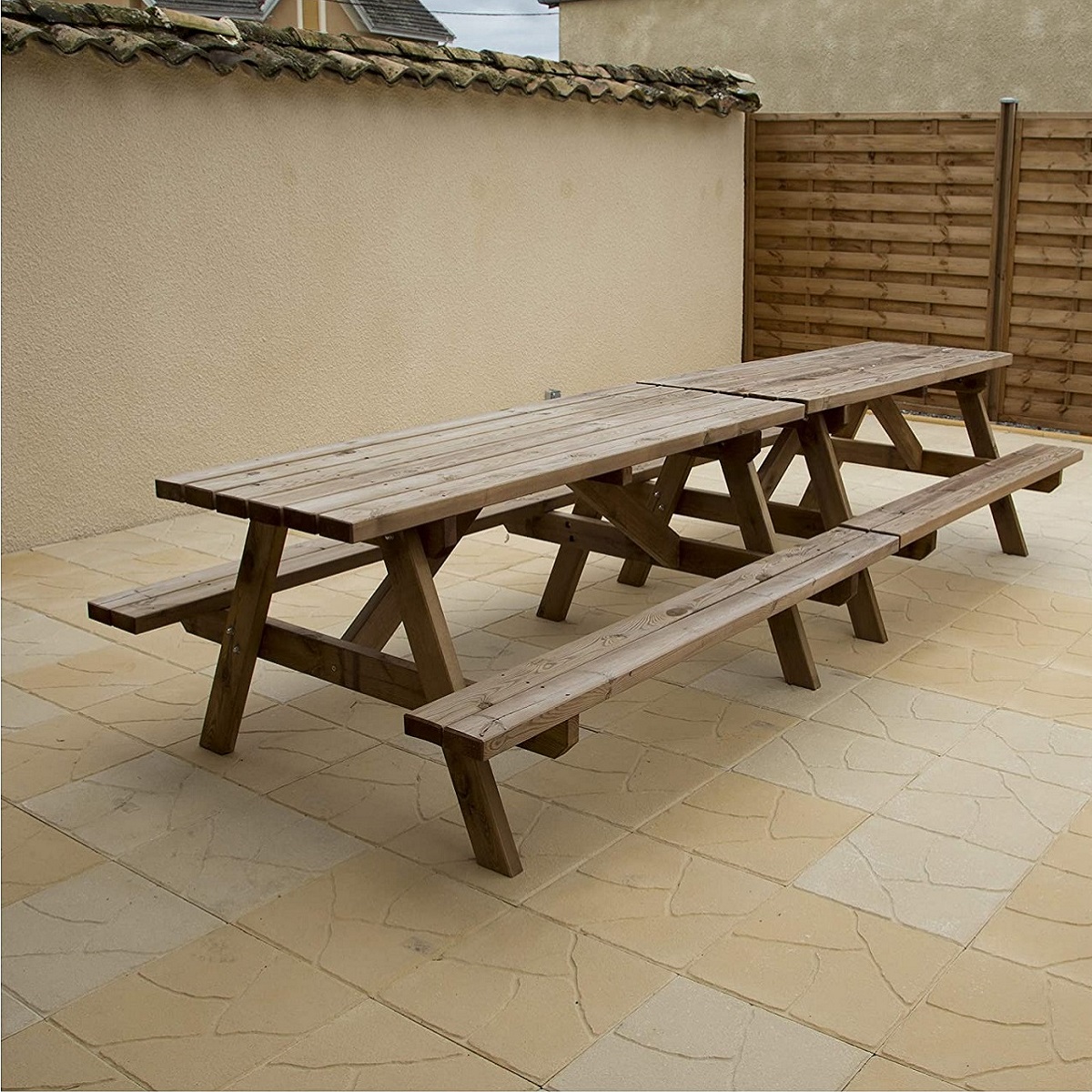 Outdoor wooden table and benches on a patio with Indian sandstone paving.
