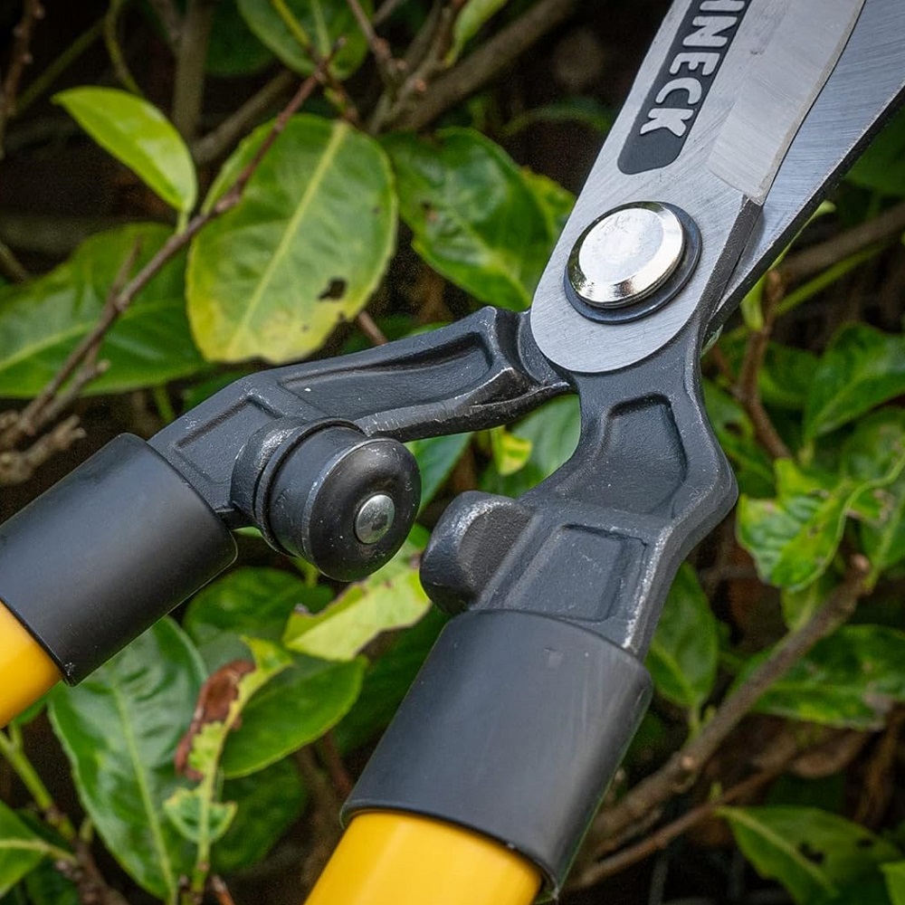 Close-up of Roughneck XT PRO Heavy Duty Wavy Blade Hedge and Grass Shears cutting through green foliage.
