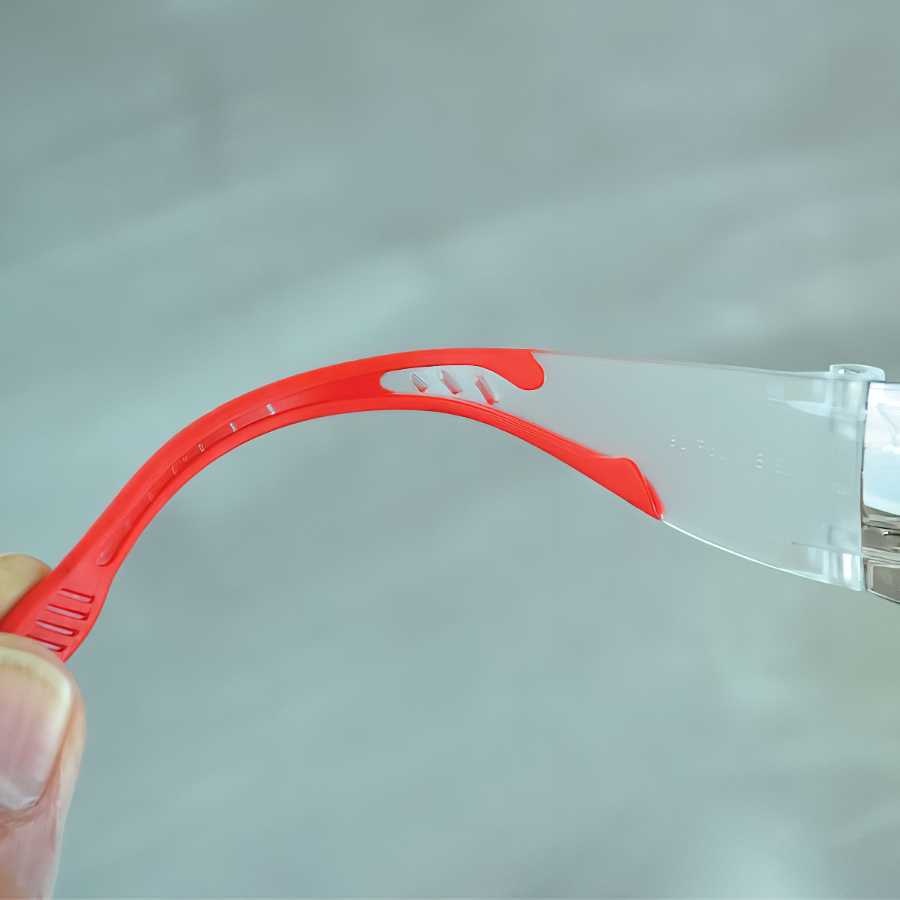 Close-up of red and clear safety glasses arm with flexible design.