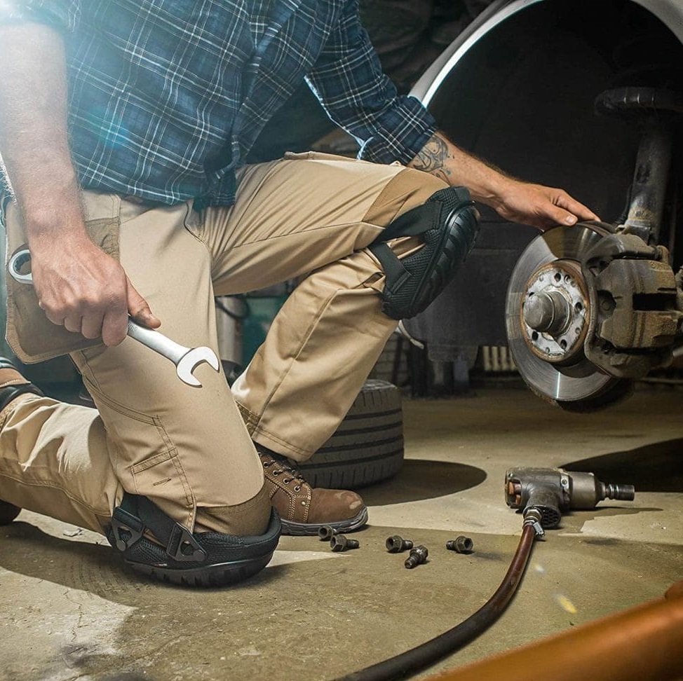 Person wearing gel knee pad protector while working on vehicle brakes.