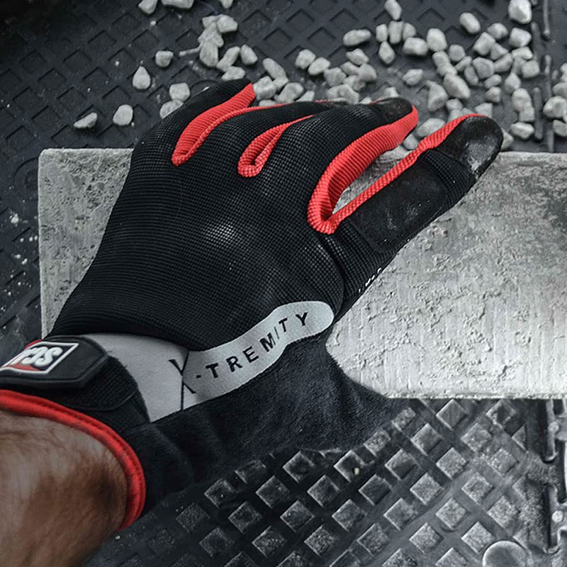 Black and red work glove gripping a concrete block on a textured surface.