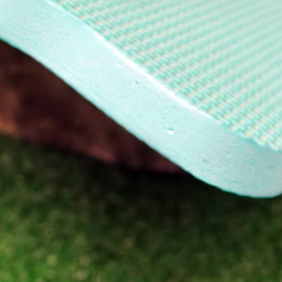 Close-up of a light green knee protection pad with textured surface on grass.