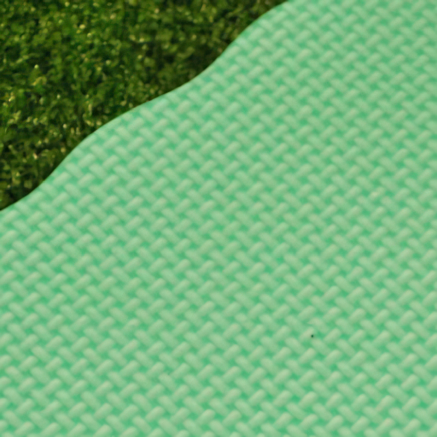 Close-up of a green knee protection pad on grass with a textured surface.