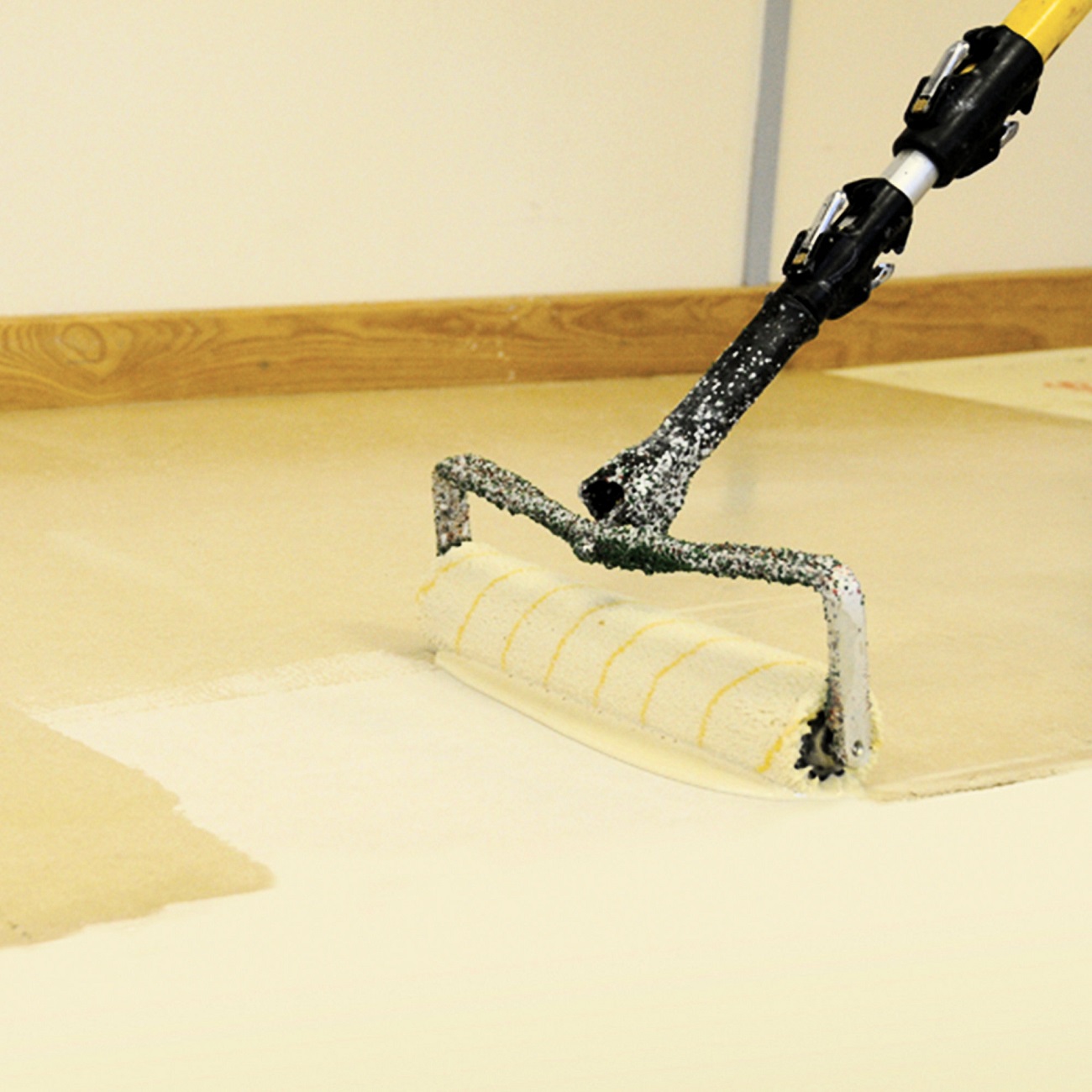 Application of Sika MB Primer Epoxy Moisture Barrier on wood flooring subfloor using a roller.