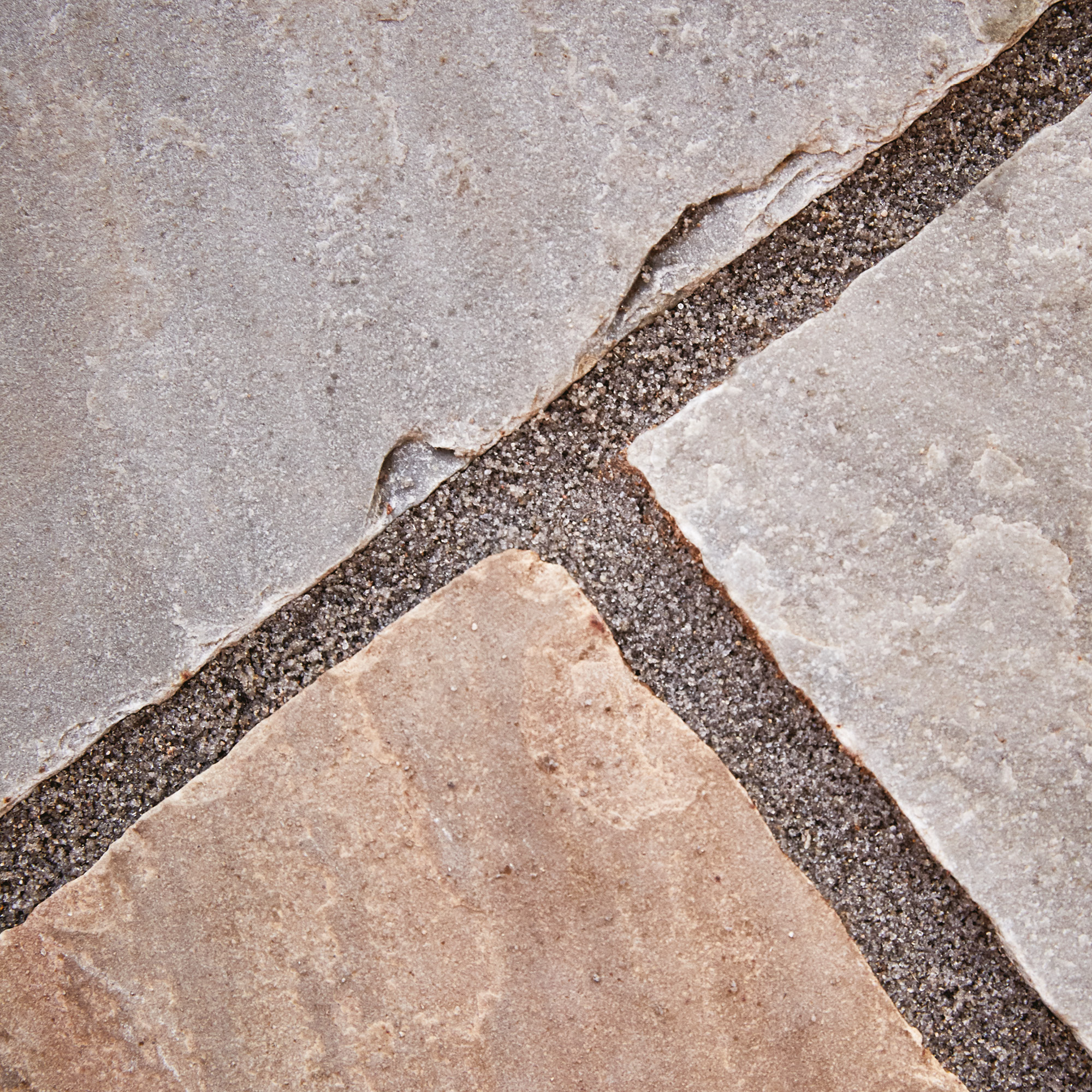Detailed close-up showing buff paving joint compound between natural stone patio slabs