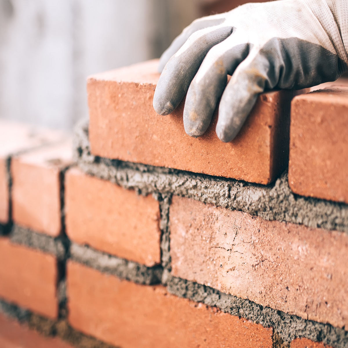 Close up of industrial bricklayer installing bricks on construction site Close up of industrial bricklayer installing bricks on construction site