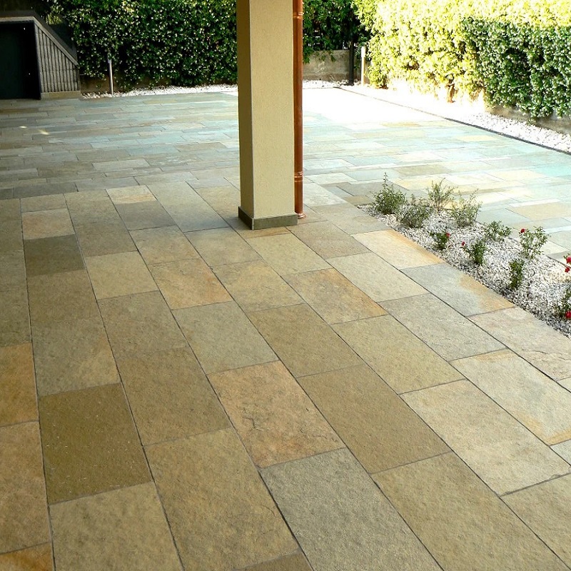 Outdoor patio with natural stone tiles and surrounding greenery.