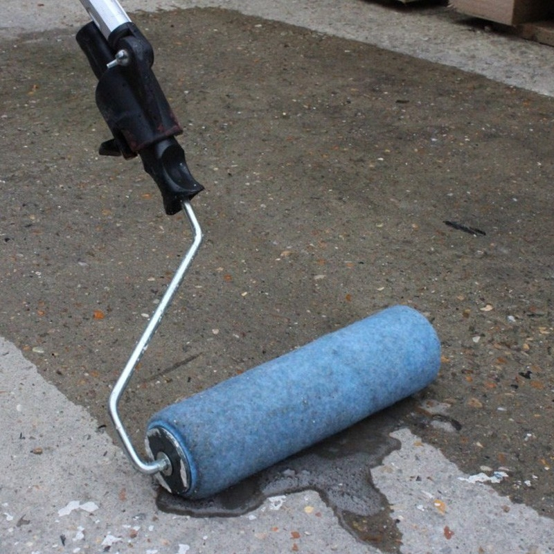 A roller applying a liquid bonding agent to concrete.