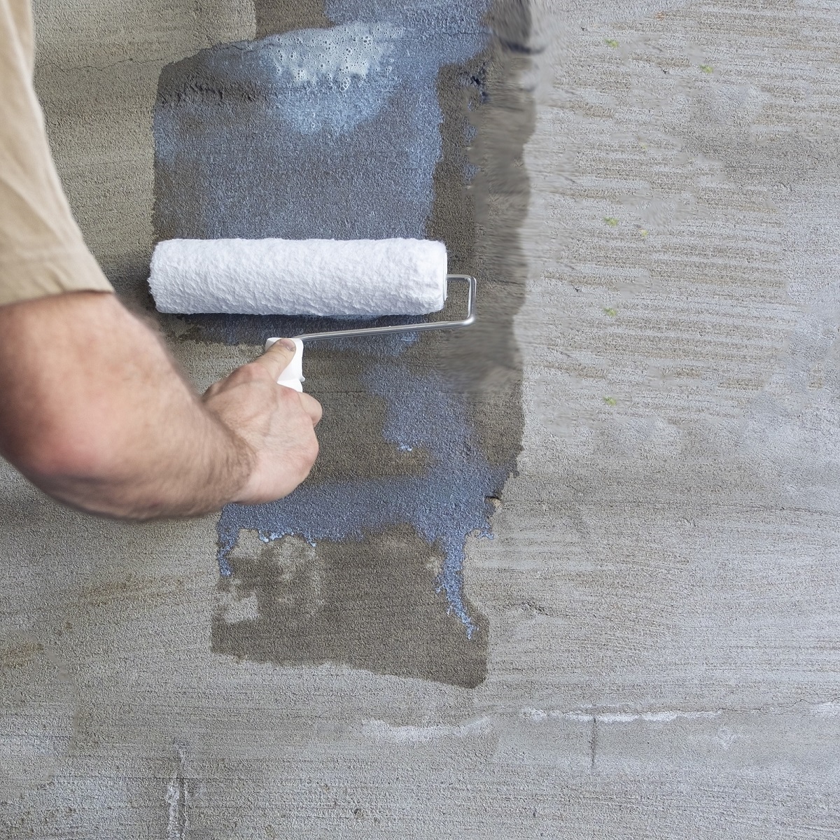 Person applying Sika SikaBond SBR+ Waterproof Bonding Agent with a roller on concrete surface.
