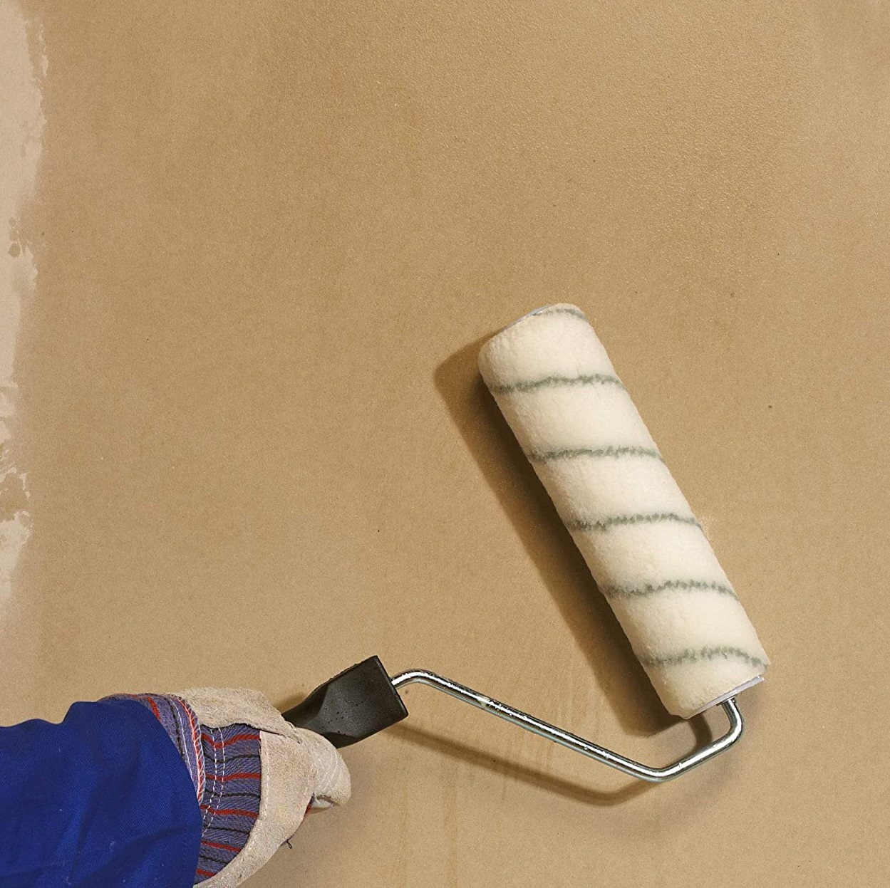 Person using a paint roller on a beige wall