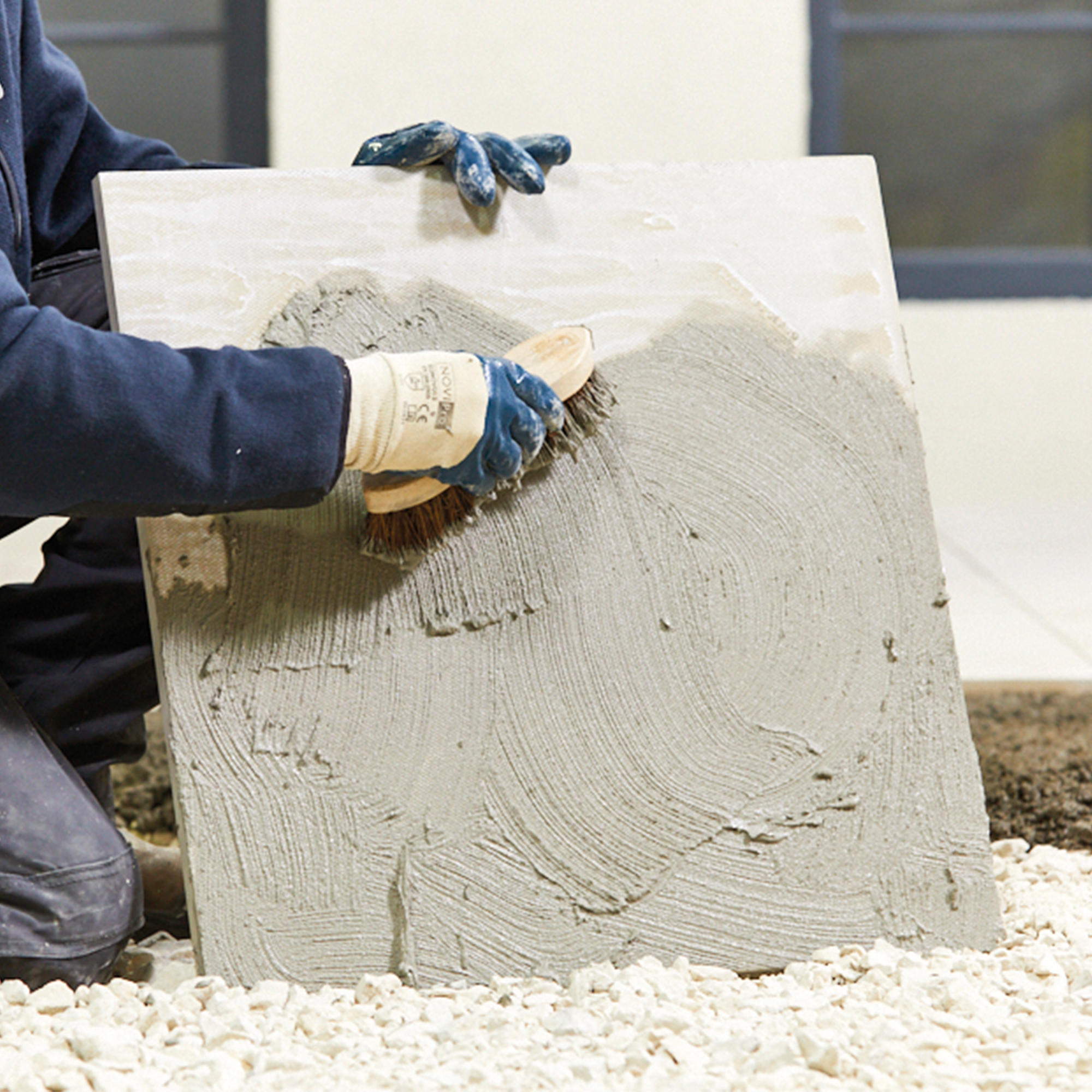 Person applying Sika Sikaceram 62 Porcelain Flowfix Bonding Slurry Primer on a tile with a brush.