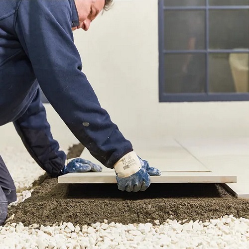 Person applying paving with Sika Sikaceram 62 Porcelain Flowfix Bonding Slurry Primer.