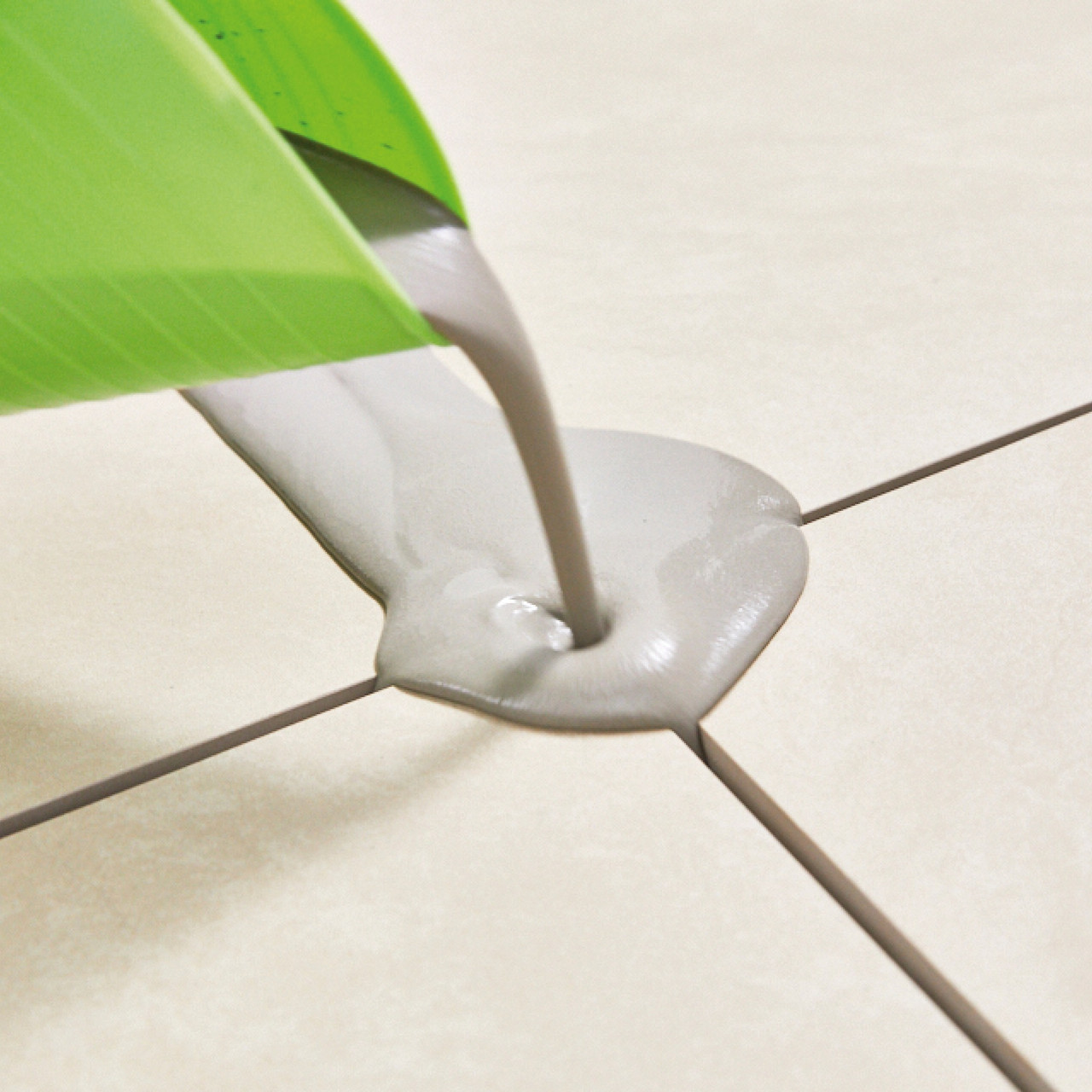 Light grey jointing compound being poured onto porcelain paving tiles.