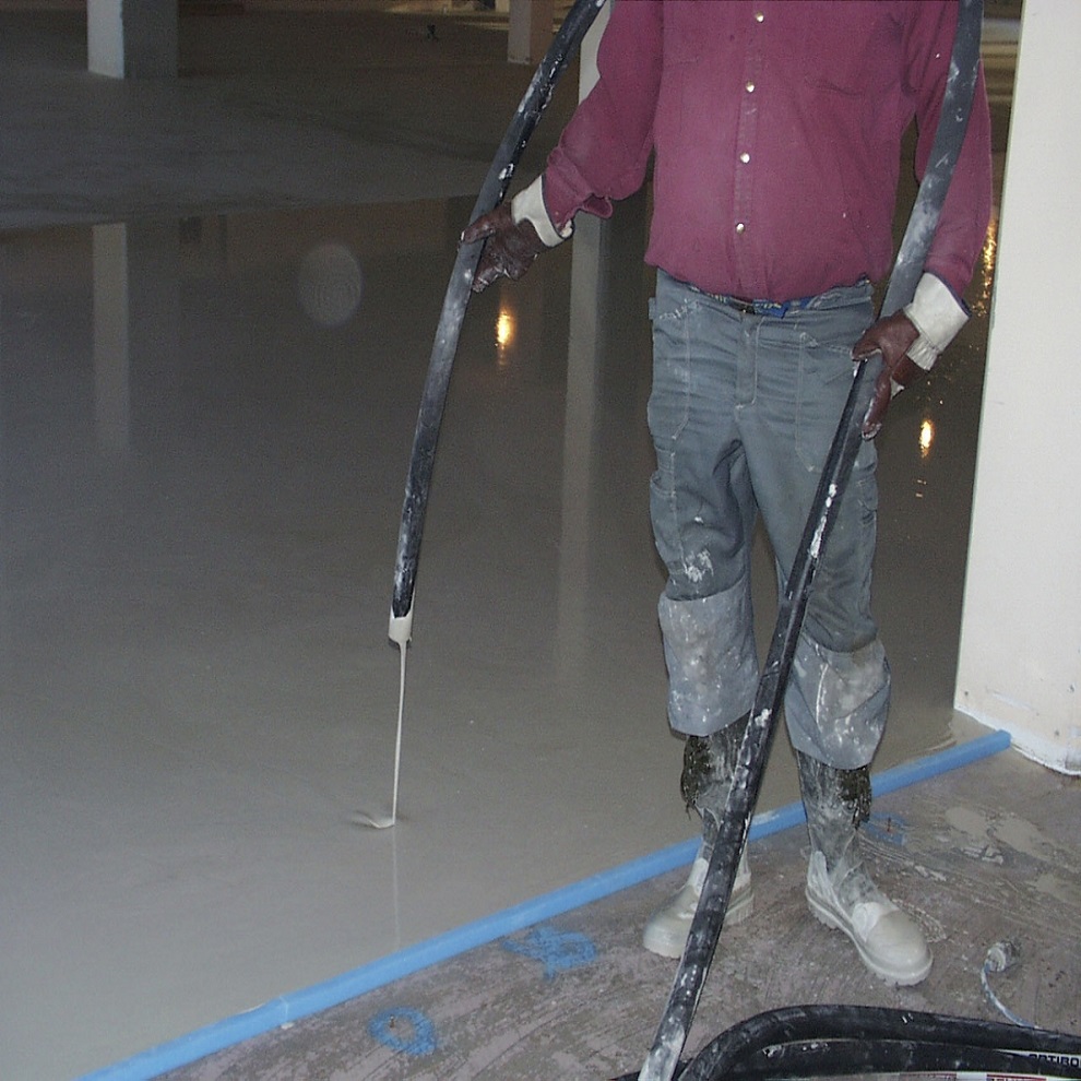 Person applying self-levelling compound on a floor.