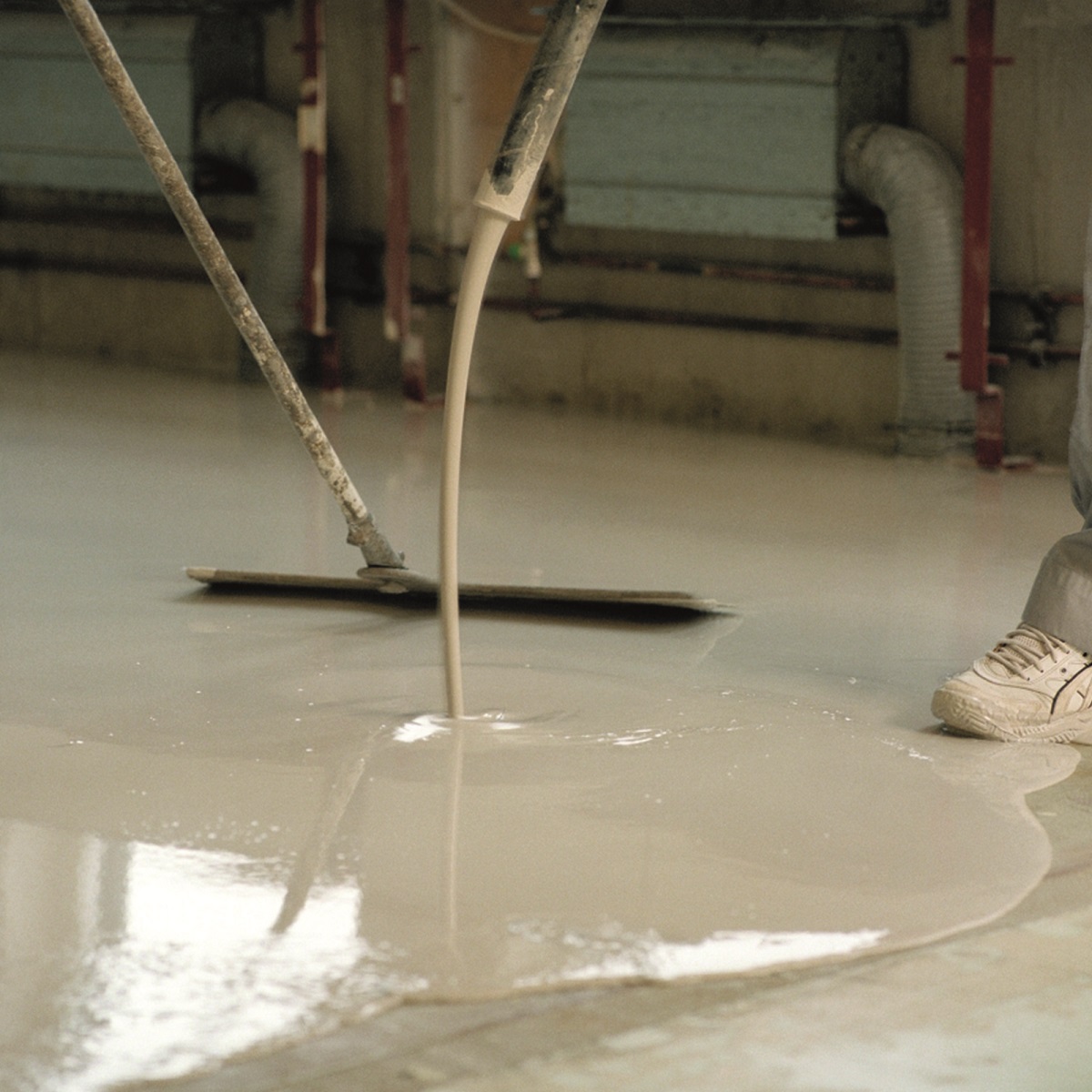 Application of self-levelling compound on a floor surface.