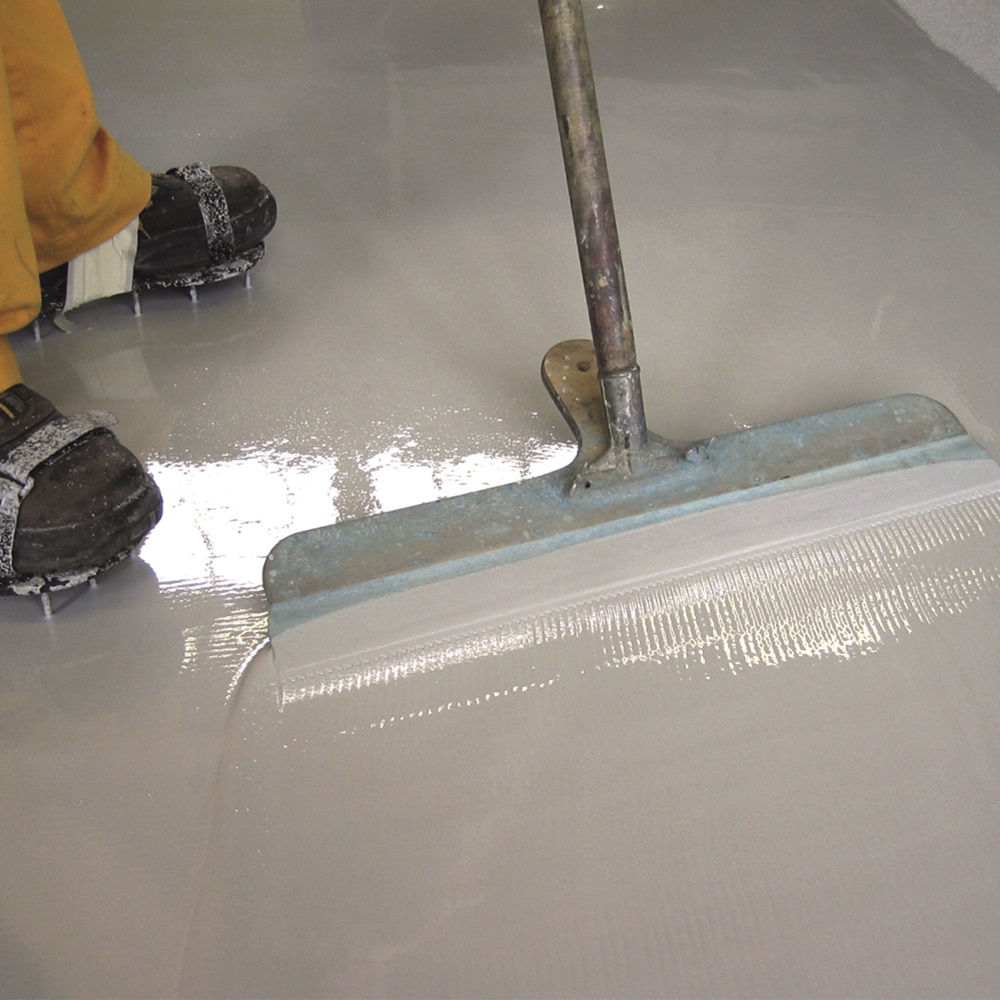 Application of Sika Sikafloor 125 Latex Self Levelling Compound on a smooth floor surface using a spreading tool.