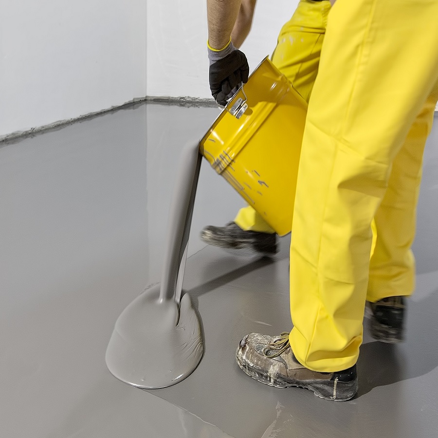 Person pouring grey self-levelling compound onto a floor.