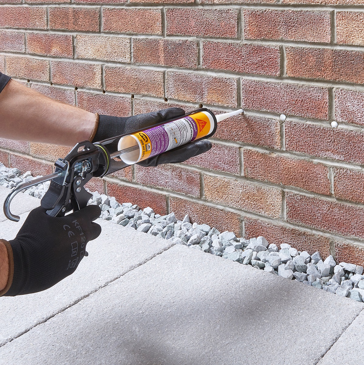 Person applying SikaMur Injectocream 100 DPC Liquid Damp Proof Membrane into brick wall.