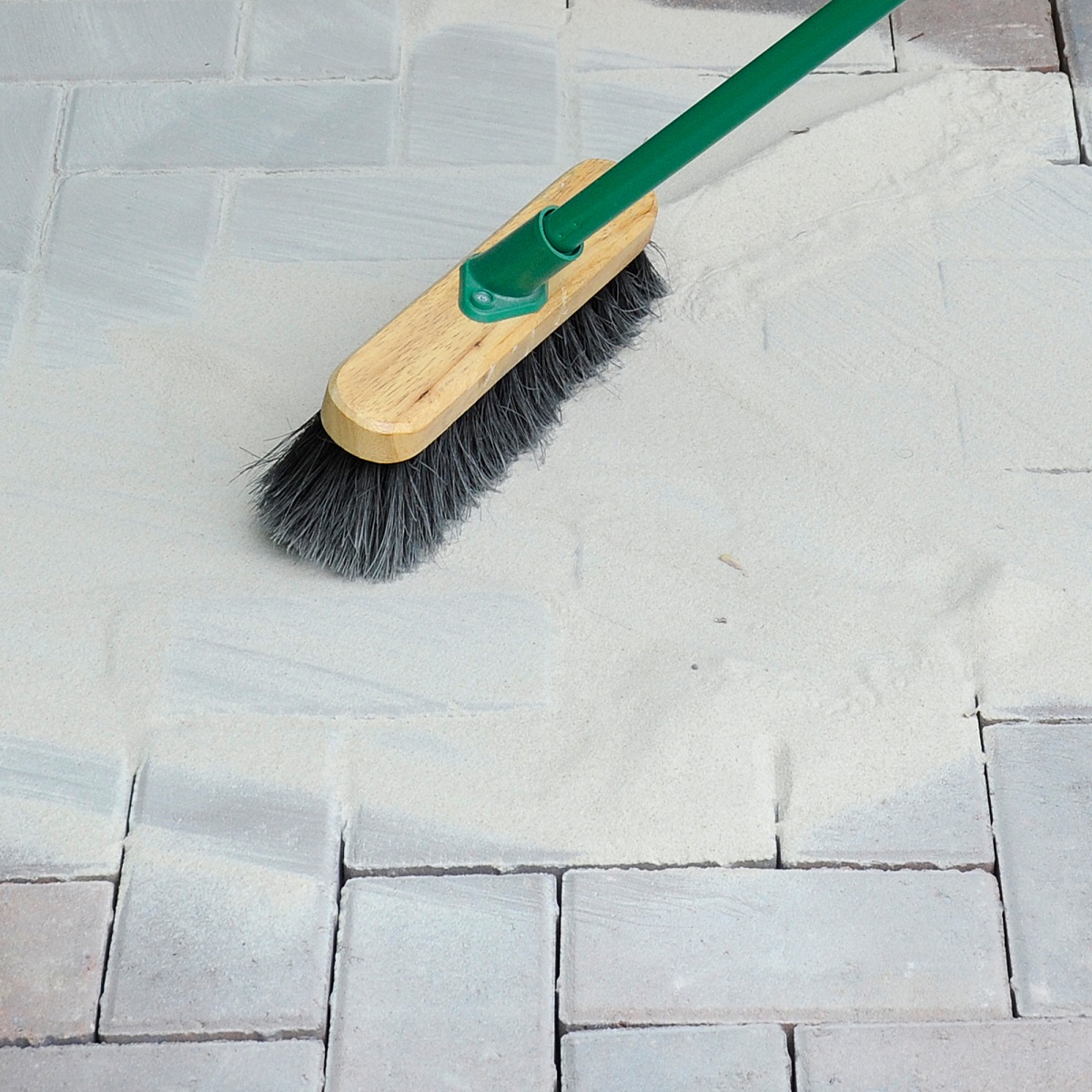 A brush spreading Sika Setting Sand on block paving joints.