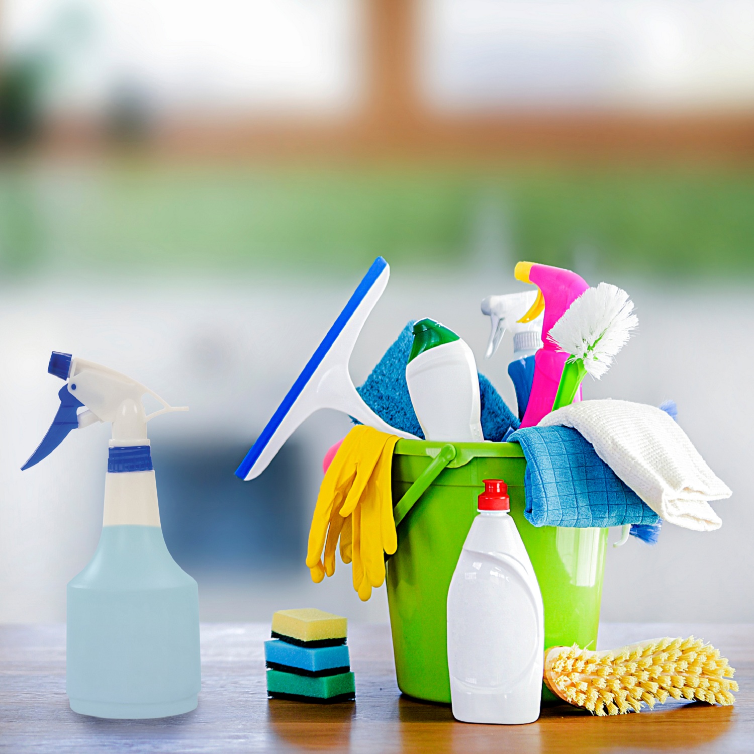 Basket or bucket with cleaning items on wooden table and blurry modern kitchen background. Washing set colorful with copy space banner. Basket or bucket with cleaning items on wooden table and blurry modern kitchen background. Washing set colorful with copy space banner.