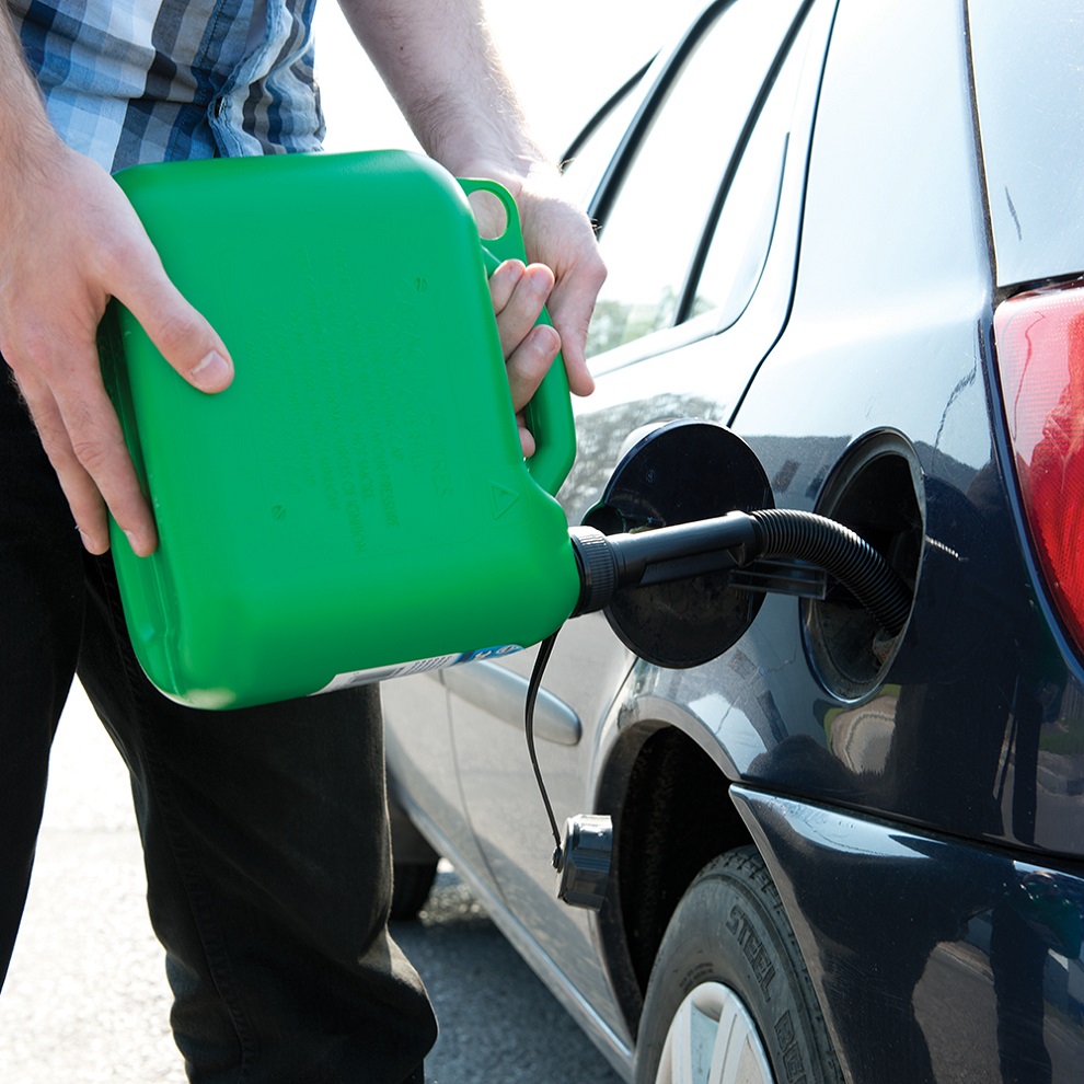 Person filling a car with fuel using a green plastic fuel can.