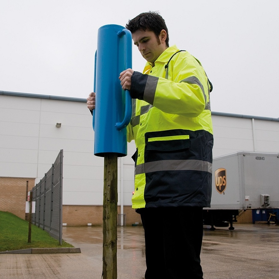 Person using a blue steel rammer tube driver to install a fence post.