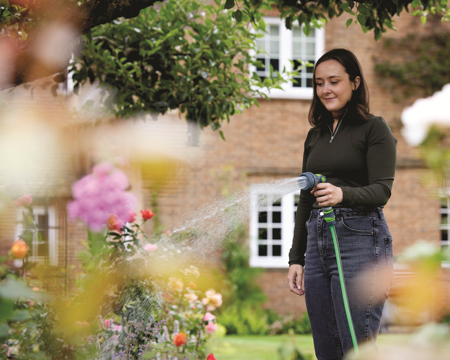 Green and grey garden hose spray water gun with connectors lady watering flowers