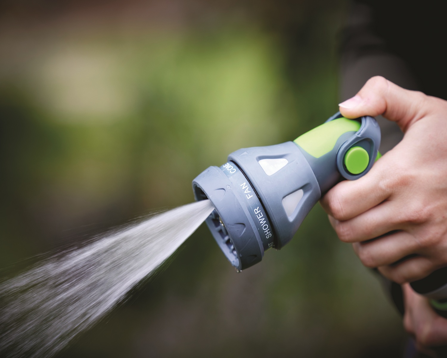 Green and grey garden hose spray water gun with connectors closeup