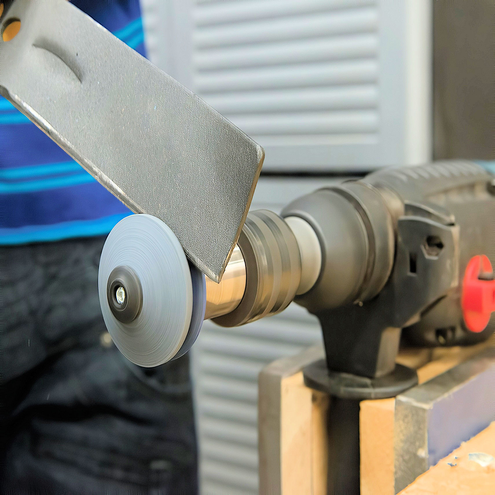 Close-up of a lawn mower blade being sharpened with a tool sharpener.