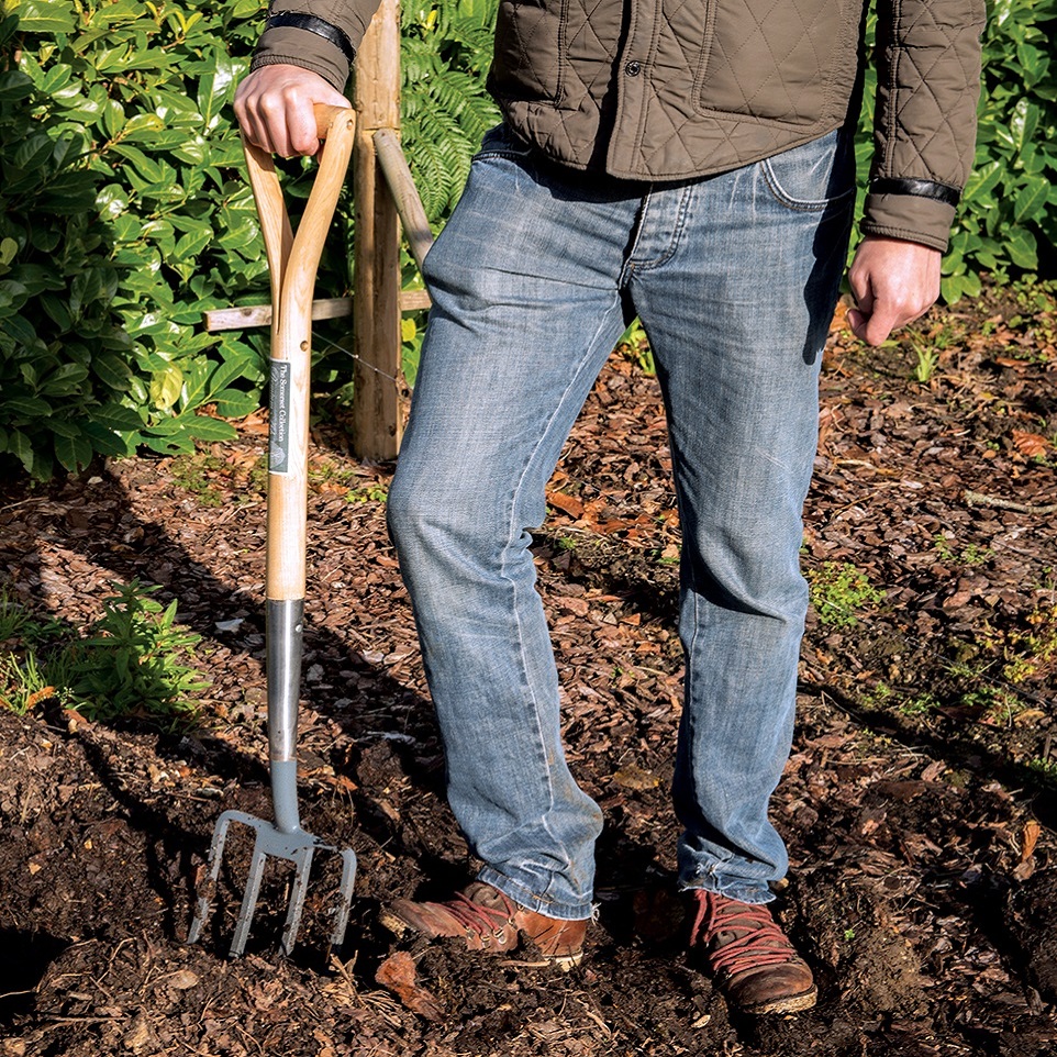 Person using a Silverline Somerset Ash Digging Fork in a garden for soil cultivation.