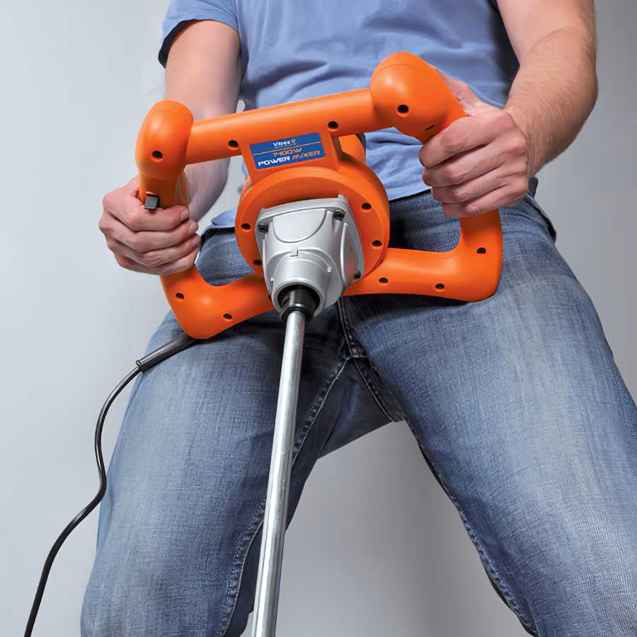 Person holding an orange Vitrex Electric Power Mixer for self levelling plaster.