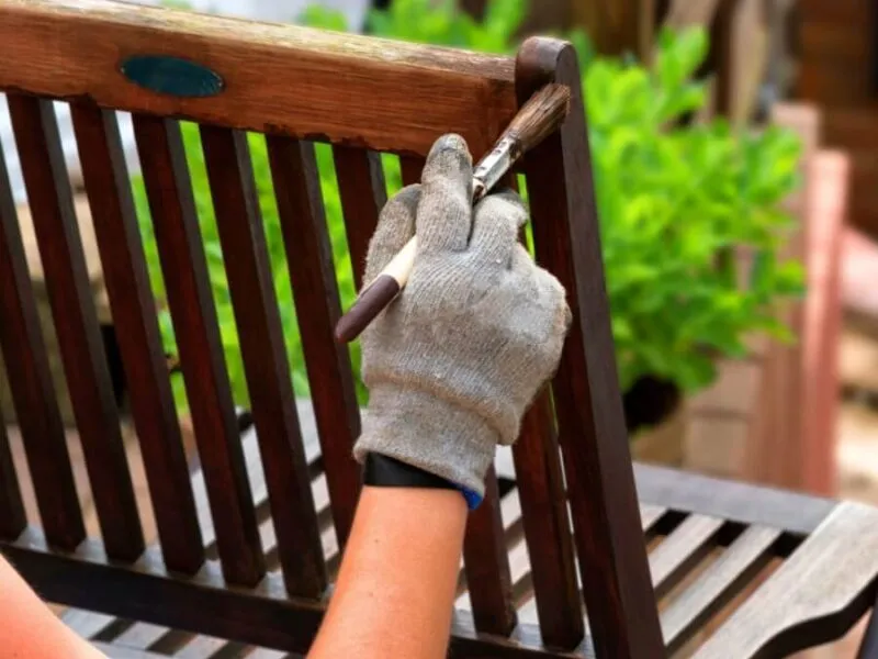 Outdoor wood chair painting activity Person painting a wooden chair with a brush outdoors