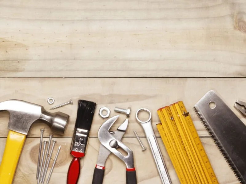 Collection of tools including hammer, wrench, and saw Assorted hand tools on a wooden surface